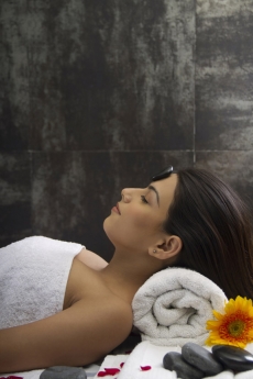 girl lying down at spa center for hot stone massage 
