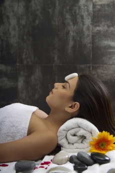 close up of a girl lying with hot stone on forehead 