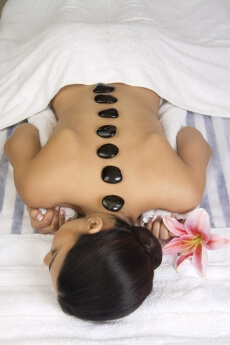 girl lying down with hot stone at the back