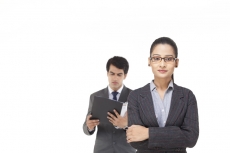 business girl posing with male executive reading file in the backgroun