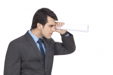 businessman with rolled paper sheets looking at something