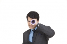 businessman looking at the camera with rolled sheet of paper