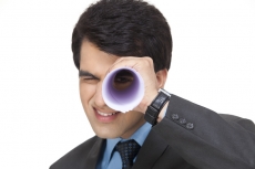 businessman smiling while looking through rolled paper sheet