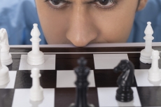man staring at chess pawns 