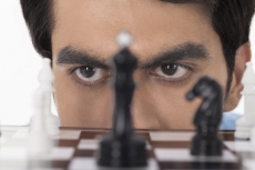 man thinking while looking at chess pawns 