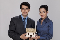 couple holding home miniature looking at the camera