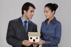 couple looking at each other while holding home miniature