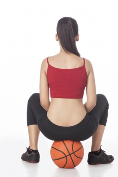 back view of girl sitting on basketball