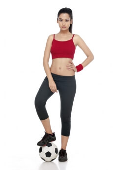 girl in sports wear posing with football