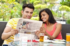 couple at breakfast table reading newspaper 