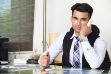 man sitting  at his office desk and talking