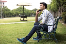 boy sitting in park and talking on phone