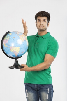 man confused and holding desktop globe 