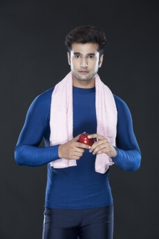 guy in gym wear carrying towel and posing with an apple 