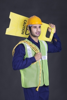 worker carrying caution stand and rope