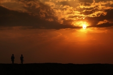 silhouette of two men standing against sun