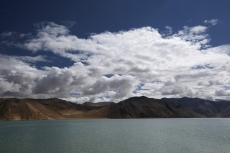 mountains surrounded by clouds along river side 