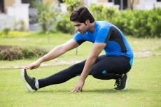 young man stretching in park 