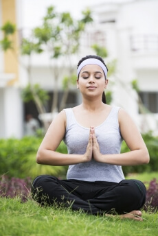 girl meditating in park with eyes closed 