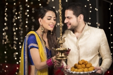 couple lighting diya and holding ladoos 