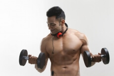 man posing with dumbbells and headphones