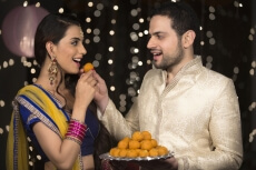 husband feeding ladoo to wife 