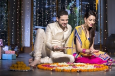 couple sitting and making rangoli on diwali