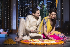 couple sitting and making rangoli on diwali