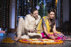 couple sitting and making rangoli on diwali