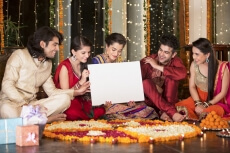 couples in traditional wear sitting with a message board 