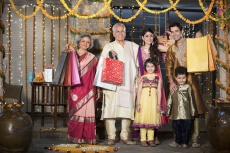 family with diwali gifts standing at entrance of house 
