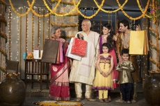family with diwali gifts standing at entrance of house 