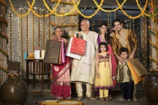 family with diwali gifts standing at entrance of house 