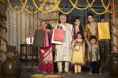 family with diwali gifts standing at entrance of house 