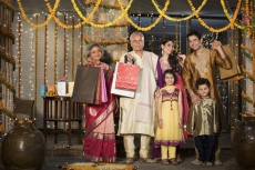 family with diwali gifts standing at entrance of house 