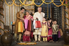 family with diwali gifts standing at entrance of house 