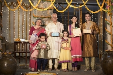 family in traditional wear standing with diwali gifts 