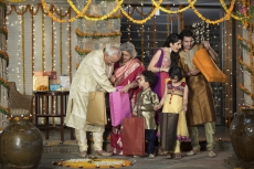 family in traditional wear standing with diwali gifts 