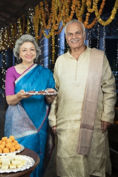 smiling old couple welcoming guests on diwali
