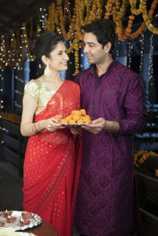 attractive young couple sharing diwali sweets