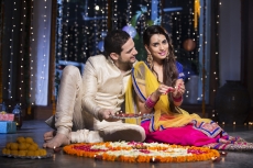 couple sitting and making rangoli on diwali