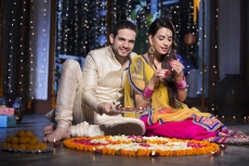 couple sitting and making rangoli on diwali
