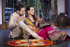 couple in traditional wear sitting with laptop