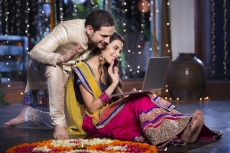 couple in traditional wear sitting with laptop