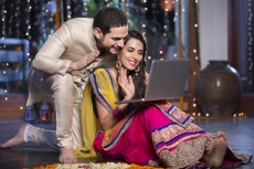couple in traditional wear sitting with laptop