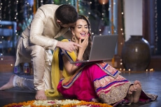 couple in traditional wear sitting with laptop