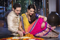 couple sitting and making rangoli on diwali