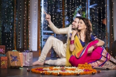 couple sitting beside flower rangoli 