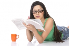 front view of a young teenage girl holding a pencil and a book