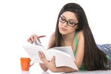 front view of a young teenage girl holding a pencil and a book